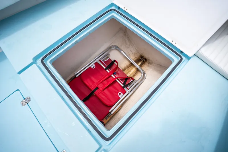 Slide: The Image of Storage compartment on 2018 Dorado 25 SE boat with red folding chair inside. - 24