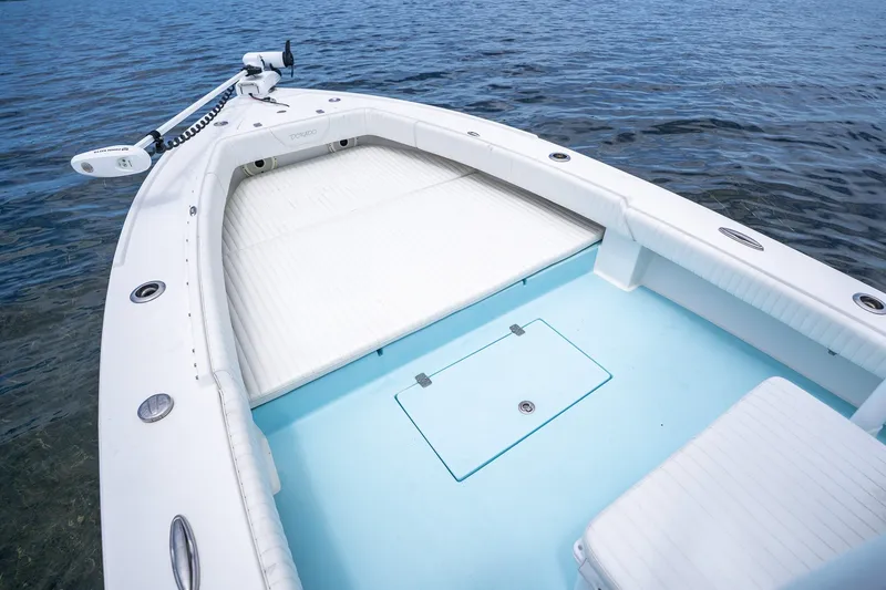 Slide: The Image of 2018 Dorado 25 SE boat deck with white seating and blue flooring on water. - 14