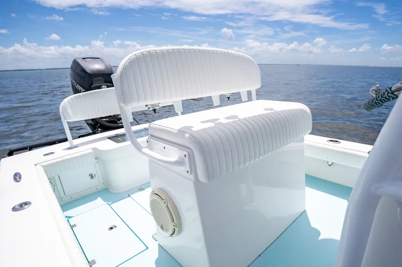 Slide: The Image of 2018 Dorado 25 SE boat interior with white seating, on calm water under blue sky. - 33