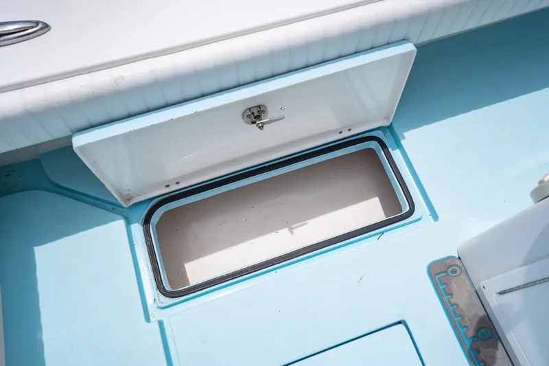 Slide: The Image of Open storage compartment on a 2018 Dorado 25 SE boat, featuring light blue interior. - 64