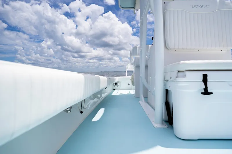 Slide: The Image of 2018 Dorado 25 SE boat interior with white seating, under a cloudy sky. - 44