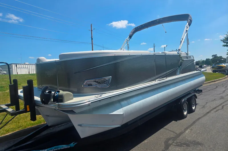 Slide: The Image of 2020 Avalon LSZ Cruise Rear Bench 22' pontoon boat on trailer under clear blue sky. - 5