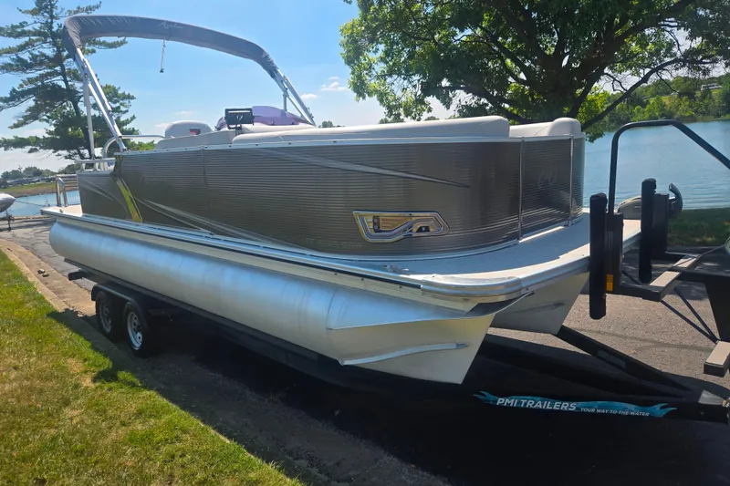 Slide: The Image of 2020 Avalon LSZ Cruise Rear Bench pontoon boat on trailer by a lakeside. - 8