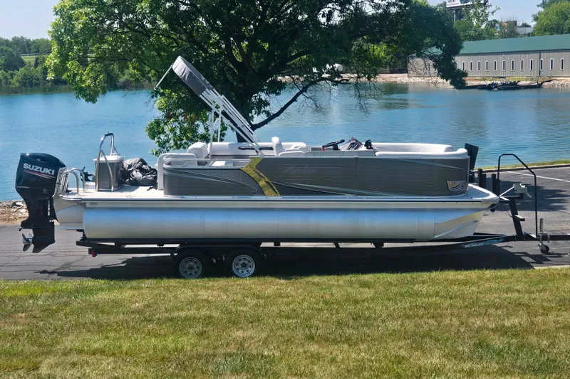 The Image of 2020 Avalon LSZ Cruise Rear Bench pontoon boat on trailer by a lake. - 0