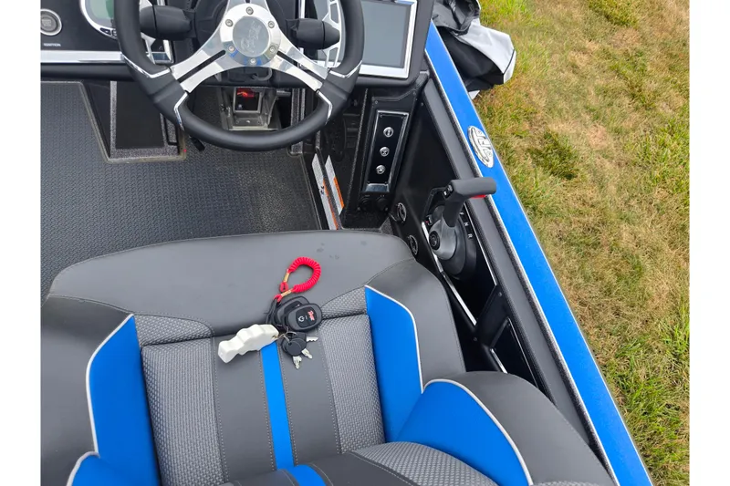 Slide: The Image of 2023 Ranger Z521R boat cockpit with steering wheel, seat, and keys on a grassy background. - 11