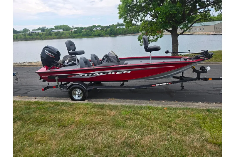 The Image of 2023 Tracker Pro Team 175 TXW boat on trailer by a lakeside road. - 10
