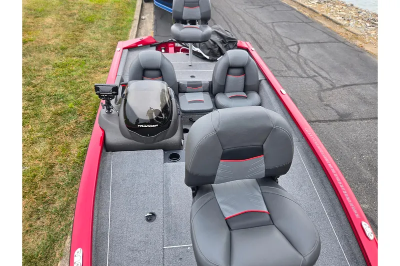 Slide: The Image of 2023 Tracker Pro Team 175 TXW boat with gray seating and red accents, docked by the shore. - 17