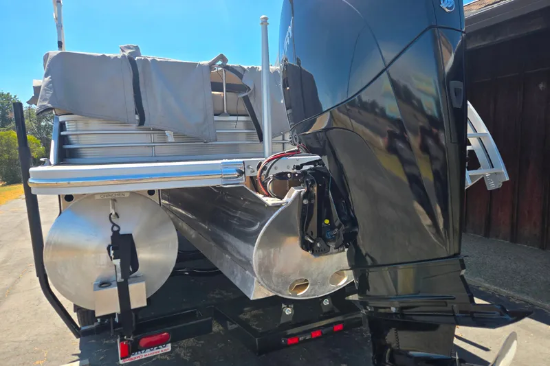 Slide: The Image of 2022 Bennington L24 pontoon boat with powerful outboard motor, parked on a trailer. - 5