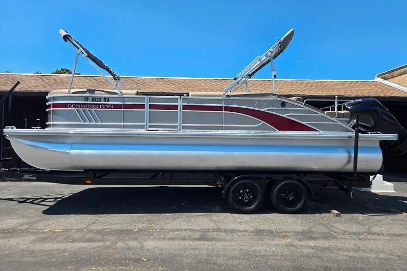 The Image of 2022 Bennington L24 pontoon boat on trailer, featuring sleek design and modern amenities. - 1