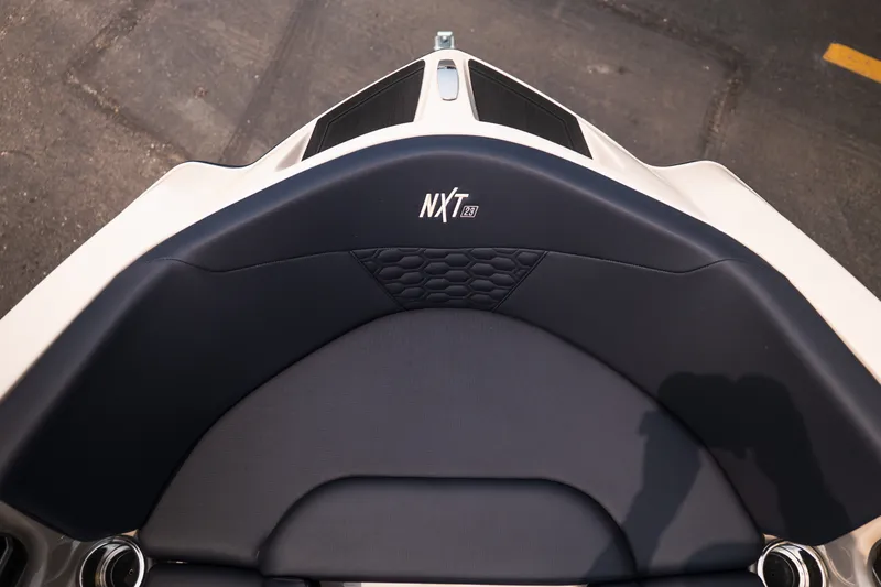 Slide: The Image of 2027 MasterCraft NXT23 boat interior with sleek seating design and logo detail. - 27
