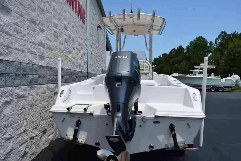 Slide: The Image of 2015 Sportsman Open 212 Center Console boat with outboard motor, parked near a building. - 4