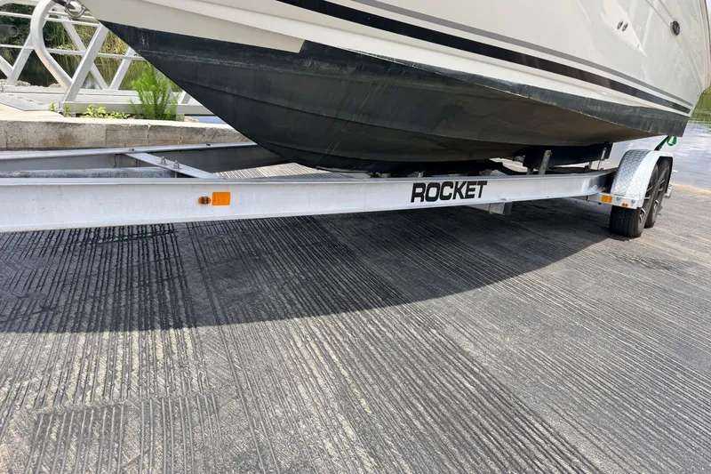 Slide: The Image of 2007 Sea Ray 240 Sundancer on Rocket trailer, parked on textured pavement. - 1