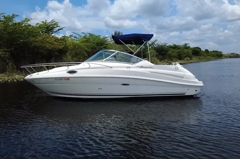 Slide: The Image of 2007 Sea Ray 240 Sundancer boat on calm water, with lush greenery in the background. - 10