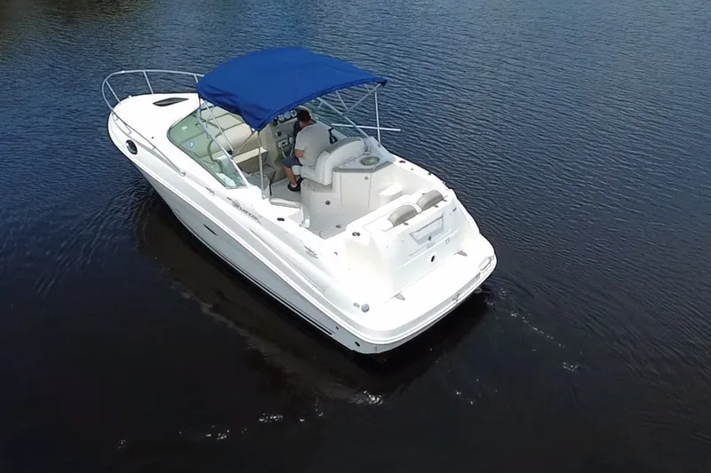 Slide: The Image of 2007 Sea Ray 240 Sundancer boat with blue canopy cruising on calm water. - 13