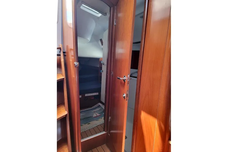 Slide: The Image of Interior view of 2003 Beneteau 423 sailboat with wooden door and cozy cabin. - 25