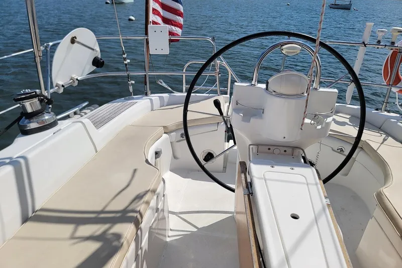 Slide: The Image of Cockpit of 2003 Beneteau 423 sailboat with steering wheel and seating, on calm water. - 32