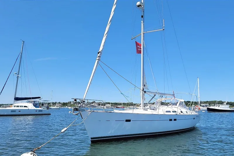 Slide: The Image of 2003 Beneteau 423 sailboat anchored in a serene harbor under a clear blue sky. - 18