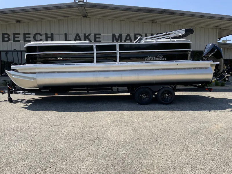 The Image of A 2027 Sun Tracker Party Barge 24 XP3 on a trailer in front of a building. - 1