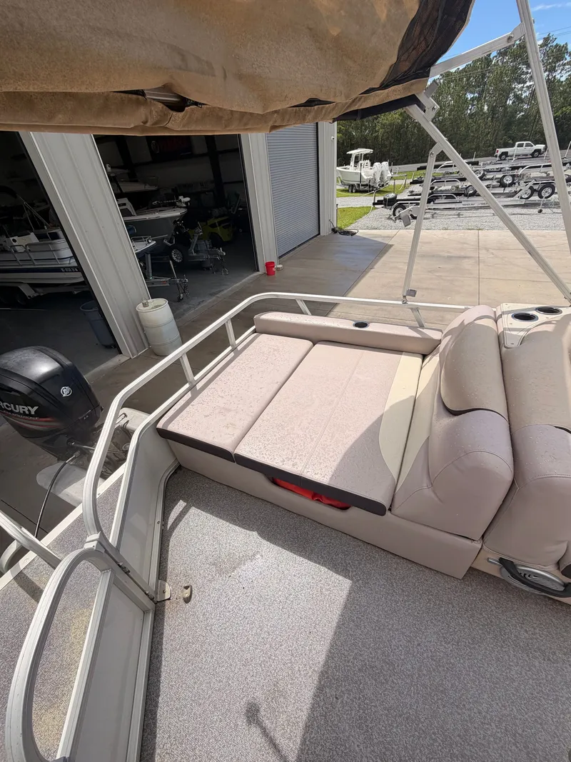 Slide: The Image of A 2015 Sun Tracker Party Barge 22 DLX with beige cushioned seating and motor in the background. - 13