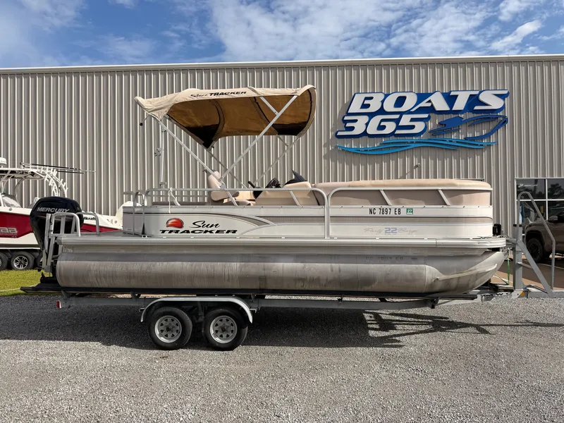 The Image of A 2015 Sun Tracker Party Barge 22 DLX on a trailer in front of a boat building. - 0