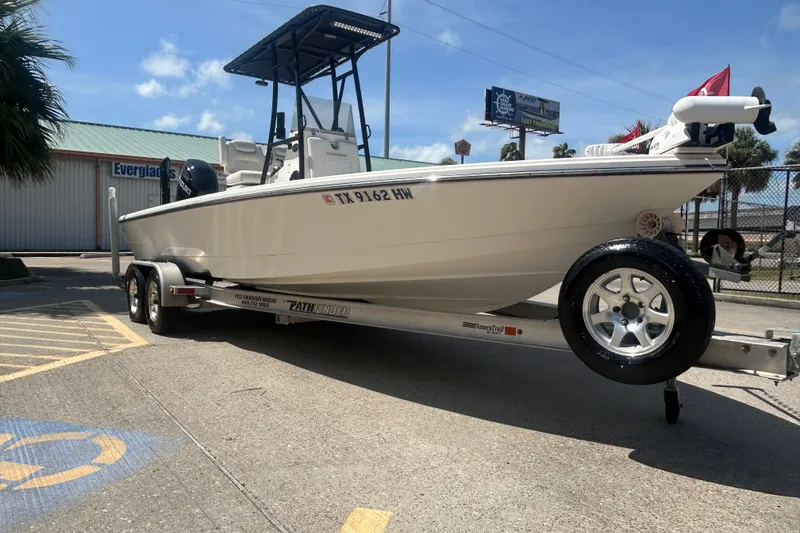 Slide: The Image of 2013 Pathfinder 2300 HPS boat on trailer, parked outdoors under clear sky. - 1