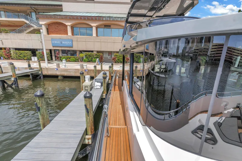 Slide: The Image of 2022 OKEAN 50 Flybridge yacht docked at Pointe Marina, showcasing sleek design and waterfront view. - 62