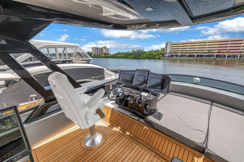 Slide: The Image of Flybridge of 2022 OKEAN 50 yacht with helm station and seating, docked by waterfront. - 68