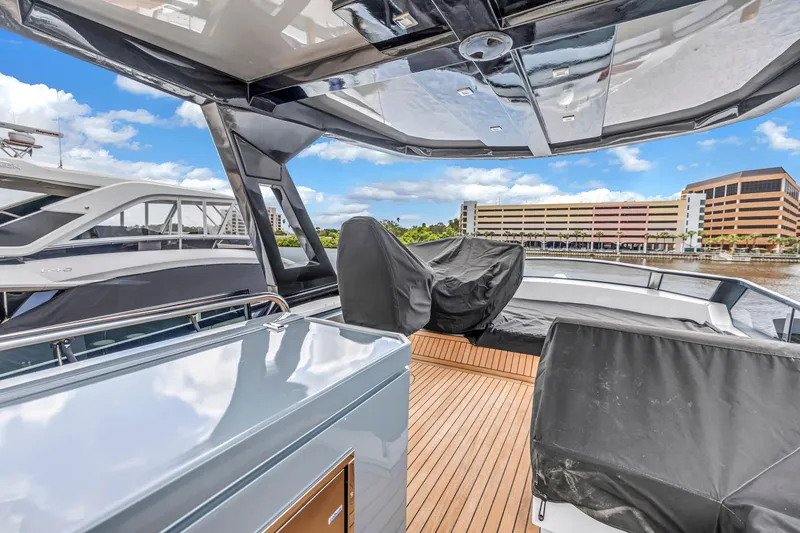 Slide: The Image of Flybridge of 2022 OKEAN 50 yacht with covered seating, docked near waterfront buildings. - 91