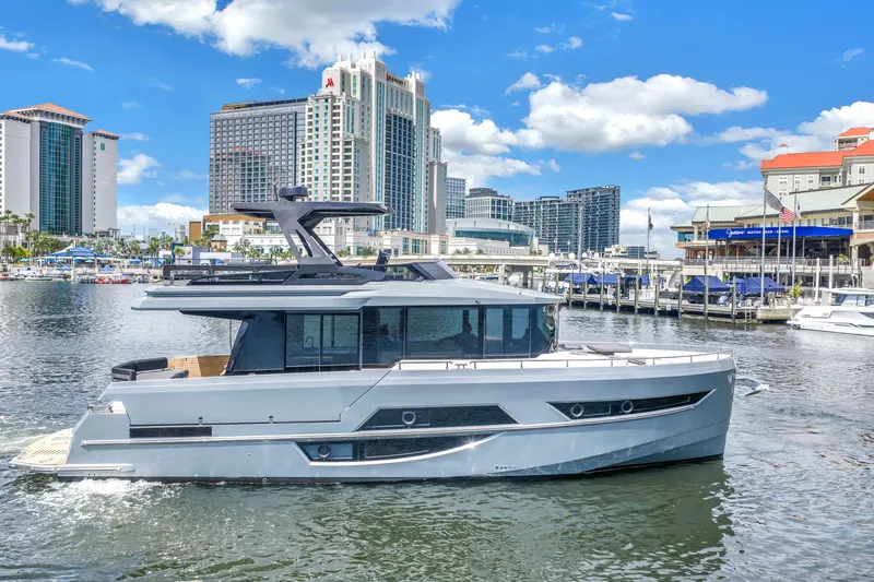 Slide: The Image of 2022 OKEAN 50 Flybridge yacht cruising in urban marina with city skyline backdrop. - 3