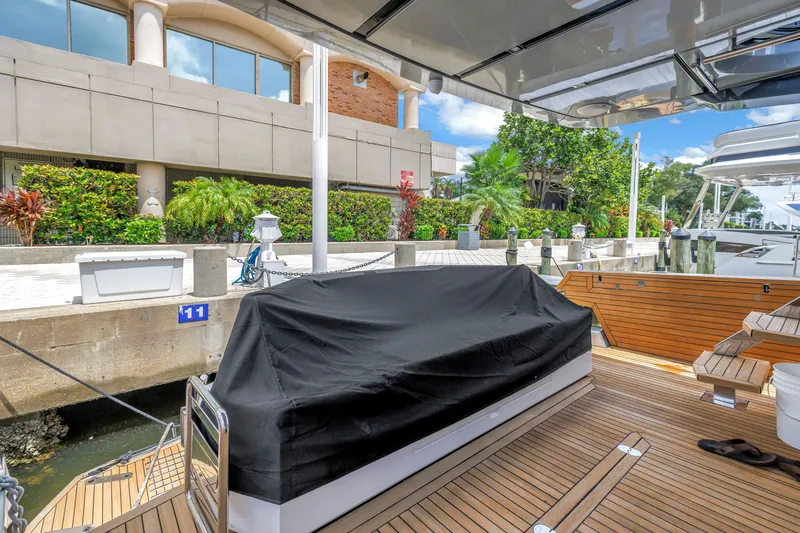 Slide: The Image of Luxury 2022 OKEAN 50 Flybridge yacht docked, featuring sleek wooden deck and covered seating area. - 88