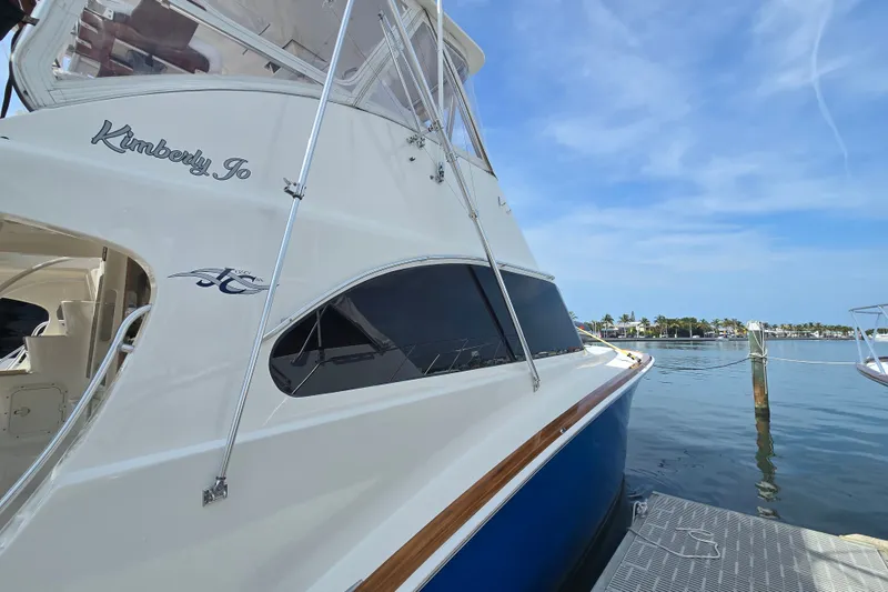 Slide: The Image of 2006 Jersey Cape 44 Convertible yacht docked by serene waterfront under clear blue sky. - 34