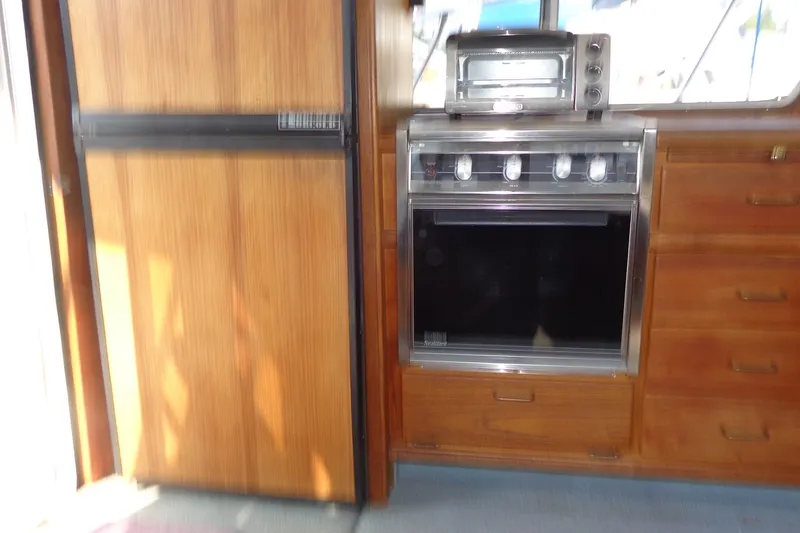 Slide: The Image of 1987 Tollycraft 34 Convertible Sedan kitchen with wooden cabinetry and stainless steel appliances. - 35