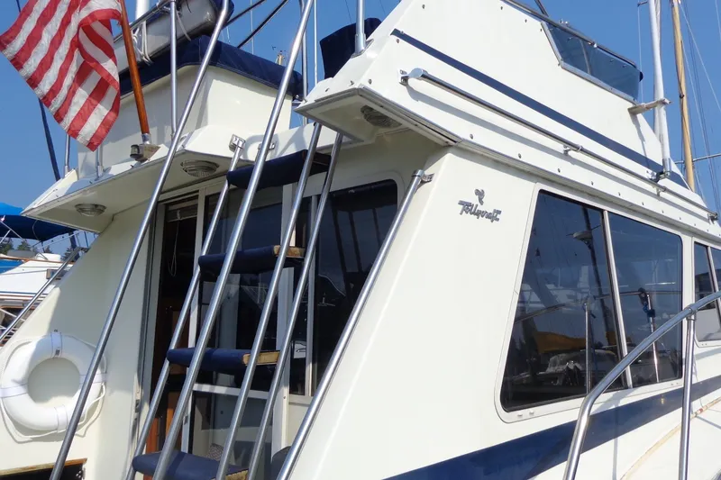 Slide: The Image of 1987 Tollycraft 34 Convertible Sedan yacht with American flag and ladder, docked in marina. - 6