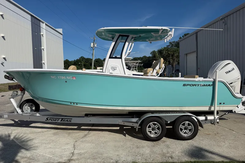 Slide: The Image of 2025 Sportsman Heritage 231 Center Console boat on trailer, turquoise hull, parked outdoors. - 2