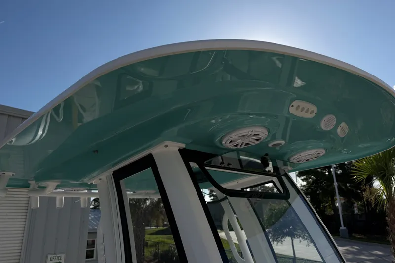 Slide: The Image of 2025 Sportsman Heritage 231 Center Console boat with teal T-top and integrated speakers. - 25