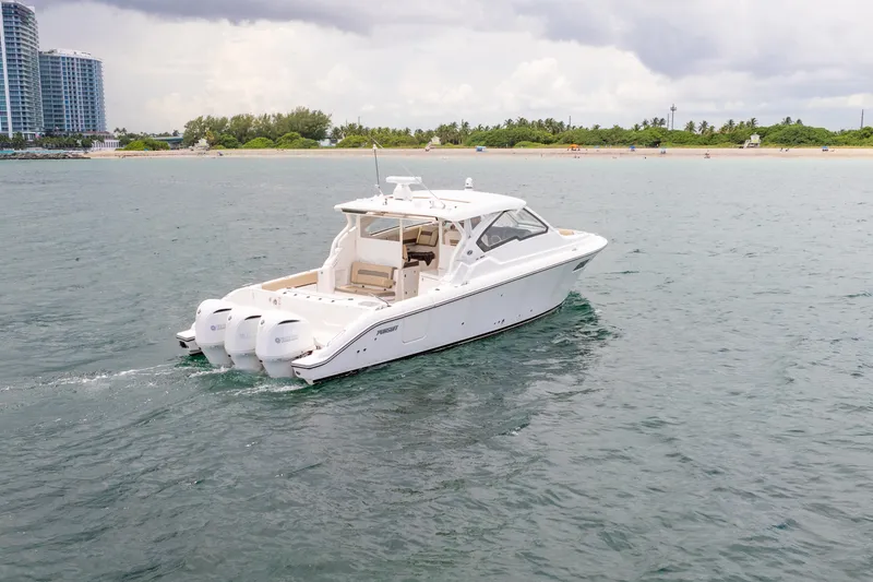Slide: The Image of 2018 Pursuit DC 365 Dual Console boat cruising near a sandy beach. - 16