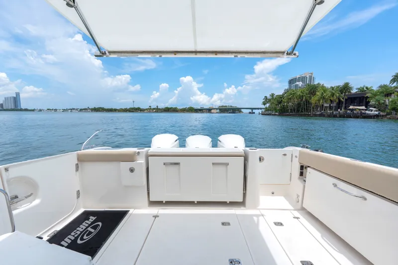 Slide: The Image of 2018 Pursuit DC 365 Dual Console boat with scenic waterfront view, clear skies, and lush greenery. - 28