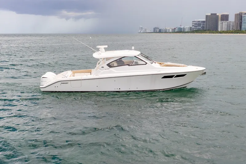 Slide: The Image of 2018 Pursuit DC 365 Dual Console boat on open water near city skyline. - 15