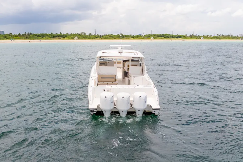 Slide: The Image of 2018 Pursuit DC 365 Dual Console boat on open water near a sandy shoreline. - 17