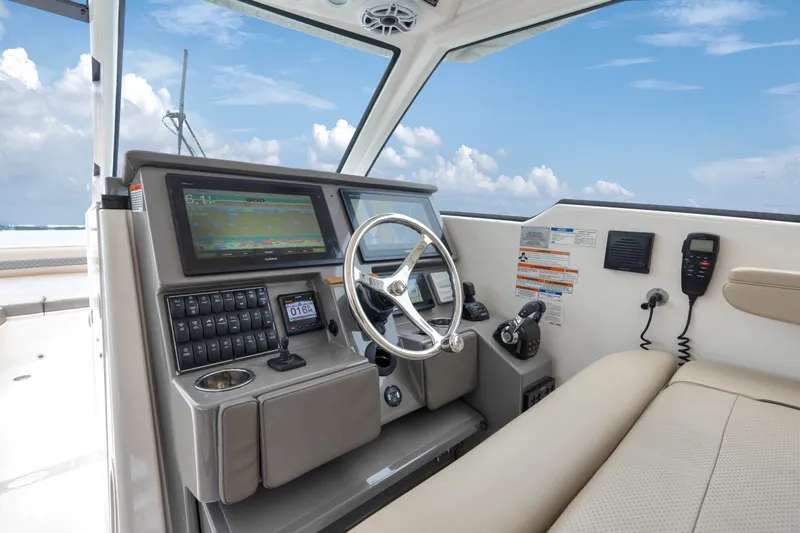 Slide: The Image of 2018 Pursuit DC 365 Dual Console boat cockpit with steering wheel and navigation controls. - 47