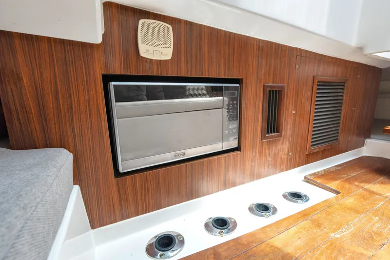 Slide: The Image of 2018 Pursuit DC 365 Dual Console interior with built-in microwave and wood paneling. - 57