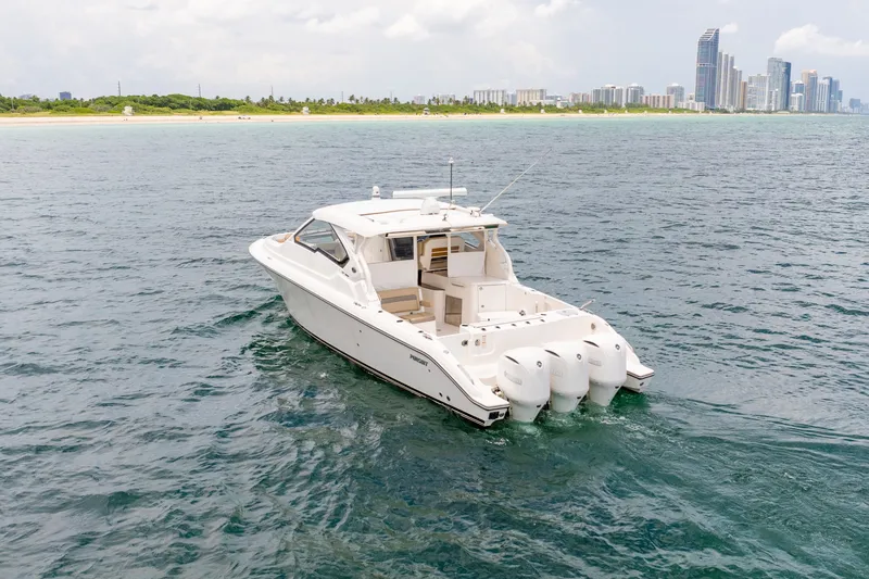 Slide: The Image of 2018 Pursuit DC 365 Dual Console boat cruising near a city skyline. - 18
