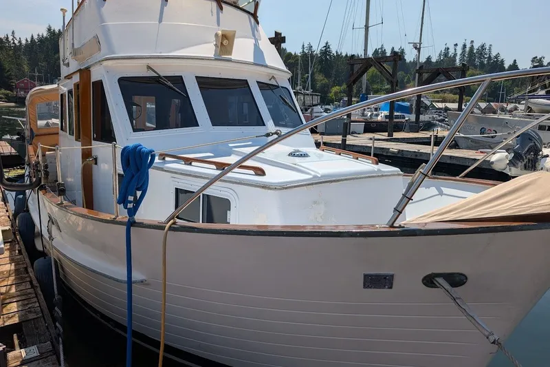Slide: The Image of 1987 Island Gypsy 32 boat docked at marina with blue rope and wooden accents. - 2