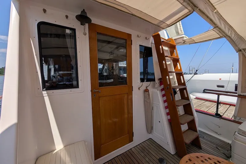 Slide: The Image of 1987 Island Gypsy 32 boat interior with wooden door and ladder under canopy. - 22