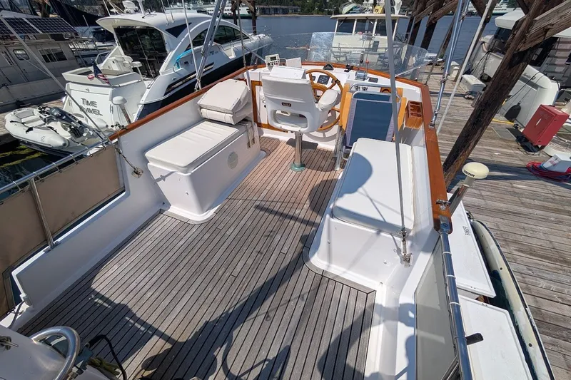 Slide: The Image of 1987 Island Gypsy 32 boat deck with seating and steering wheel at marina. - 24