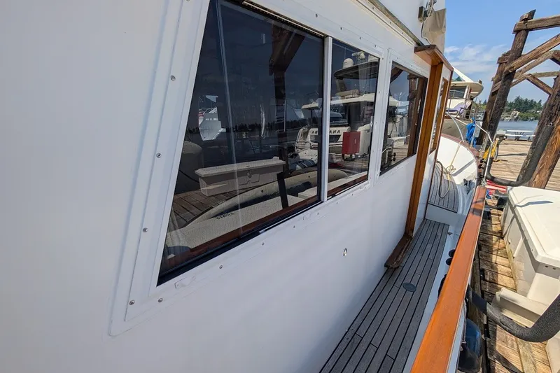 Slide: The Image of 1987 Island Gypsy 32 yacht docked, showcasing side deck and cabin windows. - 29
