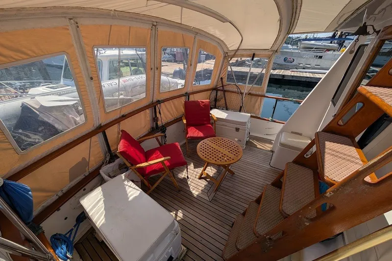 Slide: The Image of 1987 Island Gypsy 32 boat interior with seating, table, and wooden stairs in a marina setting. - 21
