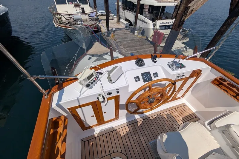 Slide: The Image of 1987 Island Gypsy 32 boat helm with wooden steering wheel and nautical instruments. - 25