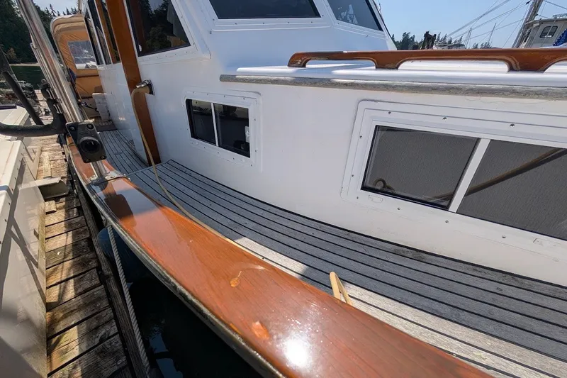 Slide: The Image of 1987 Island Gypsy 32 yacht docked, showcasing wooden deck and sleek white exterior. - 30