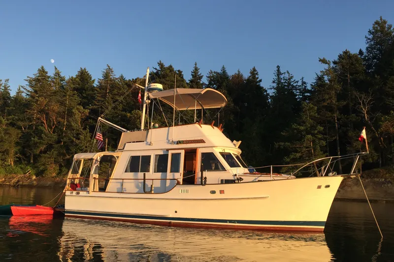 Slide: The Image of 1987 Island Gypsy 32 yacht anchored near forested shoreline at sunset. - 40